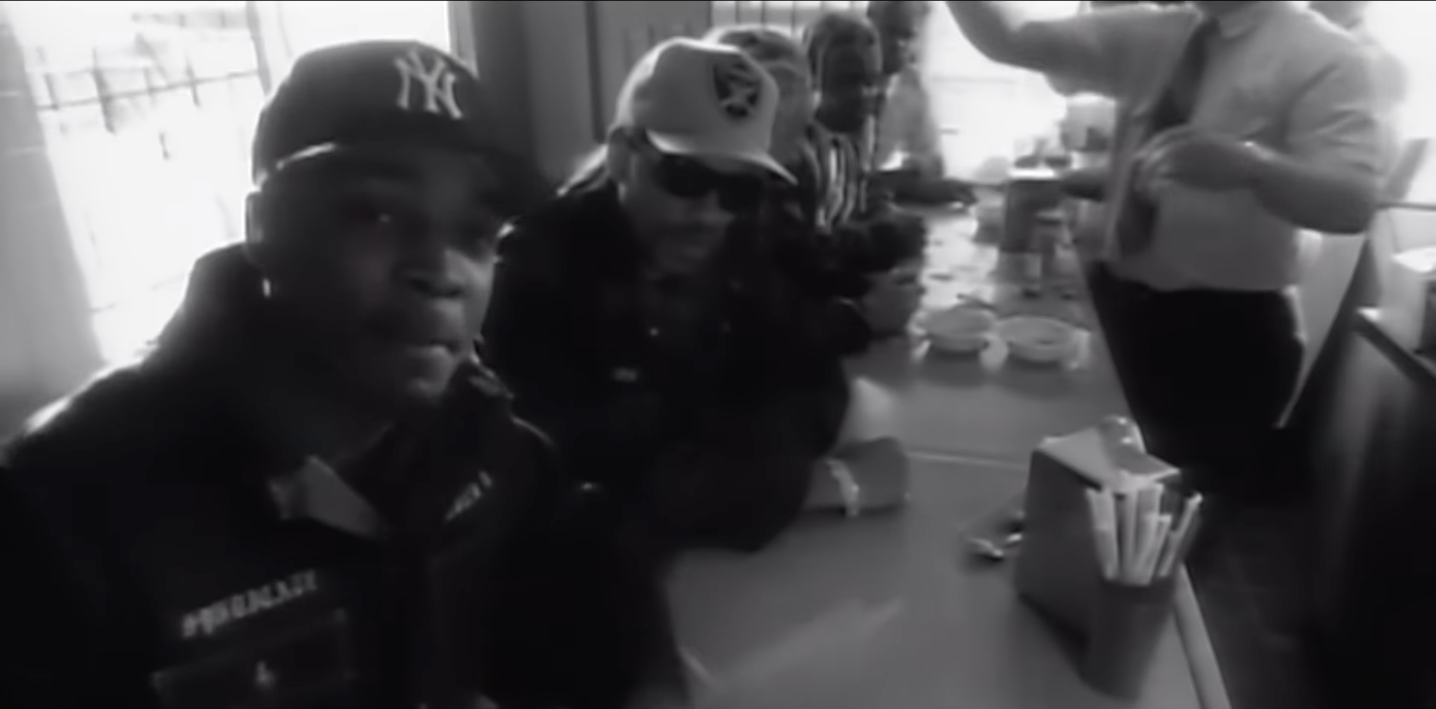 Four men sit at a diner counter as part of Public Enemy's "By the Time I Get to Arizona" Music Video.